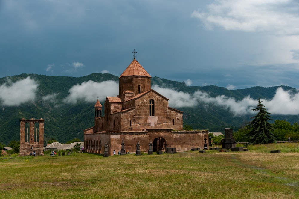 brown concrete church on green grass field under white clouds during daytime