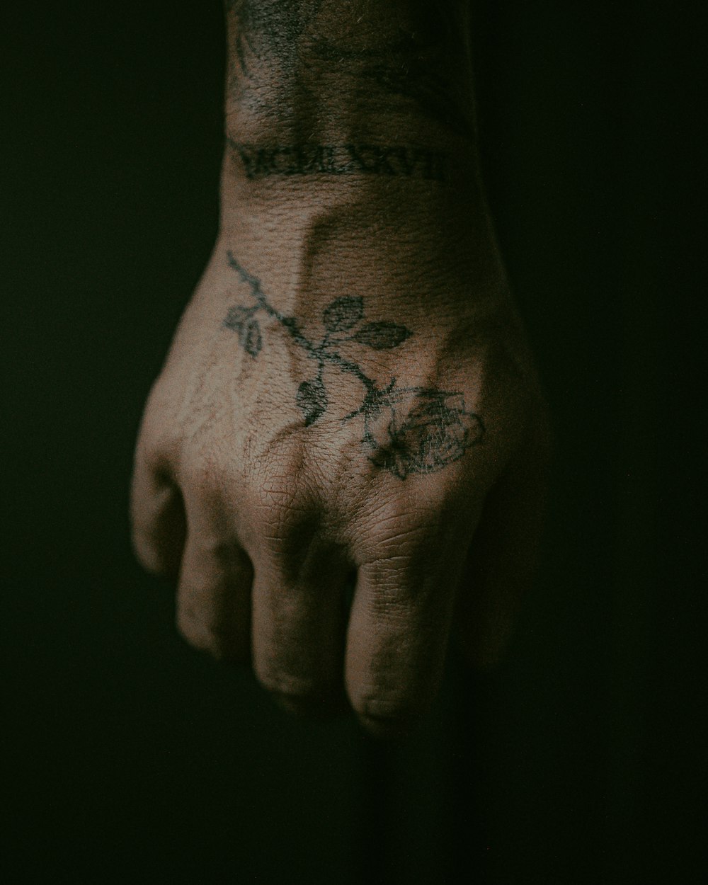 tatouage floral noir et rouge sur la main des personnes