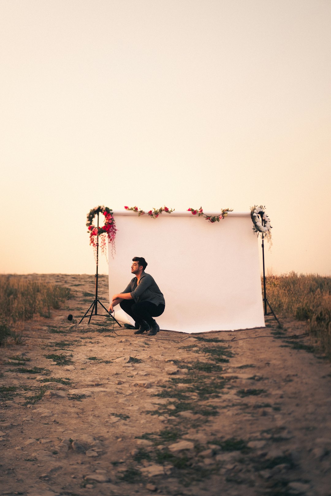 man in black shirt sitting on ground near white wall