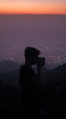 An artistic photo of a woman’s silhouette against a glowing cityscape at dusk.