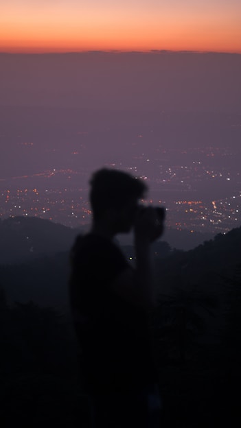 A candid shot of a photographer capturing a sunset over a bustling cityscape, highlighting the blend of natural light and urban life.