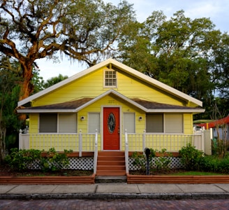 white and yellow wooden house near green trees during daytime