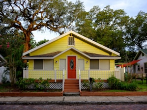 white and yellow wooden house near green trees during daytime