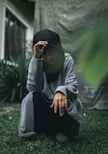 man in white thobe and black hijab sitting on green grass during daytime