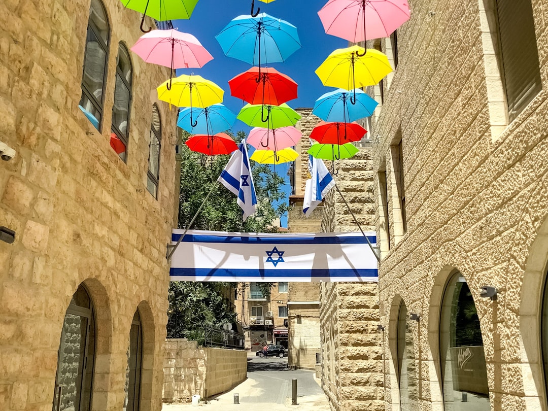 pink blue and yellow umbrella near brown concrete building during daytime