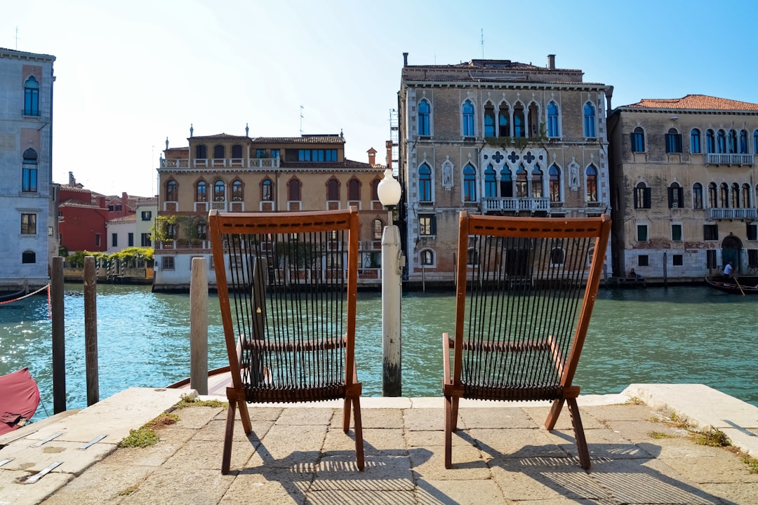 brown wooden chairs on gray concrete floor near body of water during daytime