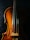 A close-up view of a wooden string instrument, focusing on the body and strings. The warm, natural wood tones contrast with the dark background, highlighting the instrument's curves and craftsmanship.
