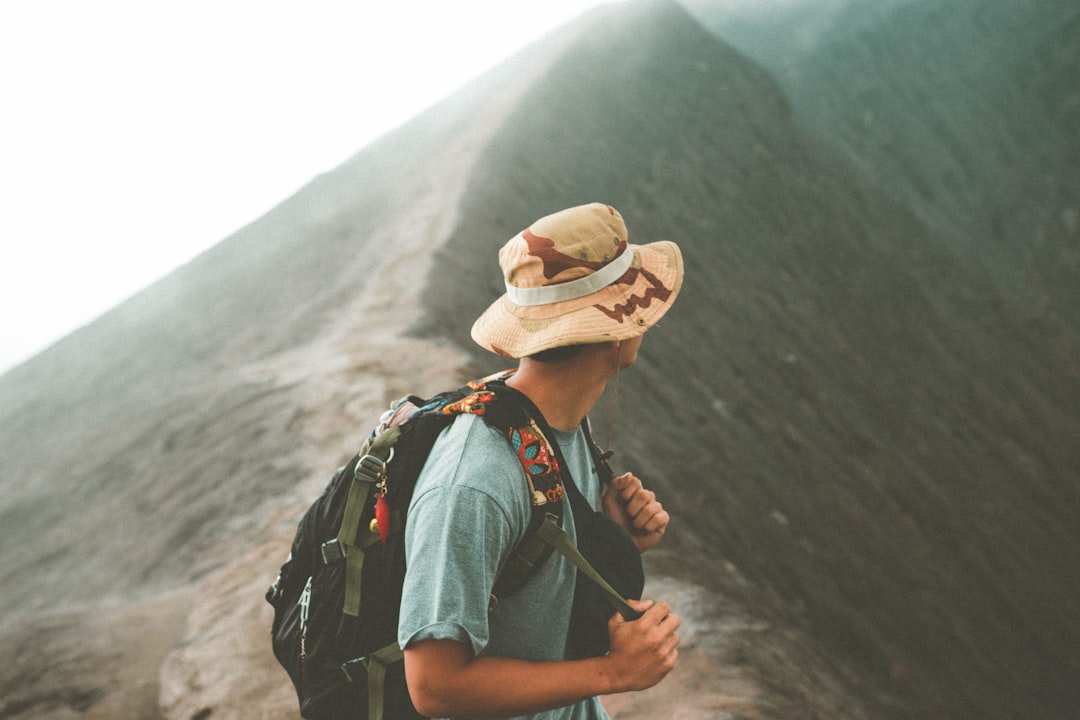 man in brown hat and blue denim jacket standing on mountain during daytime,