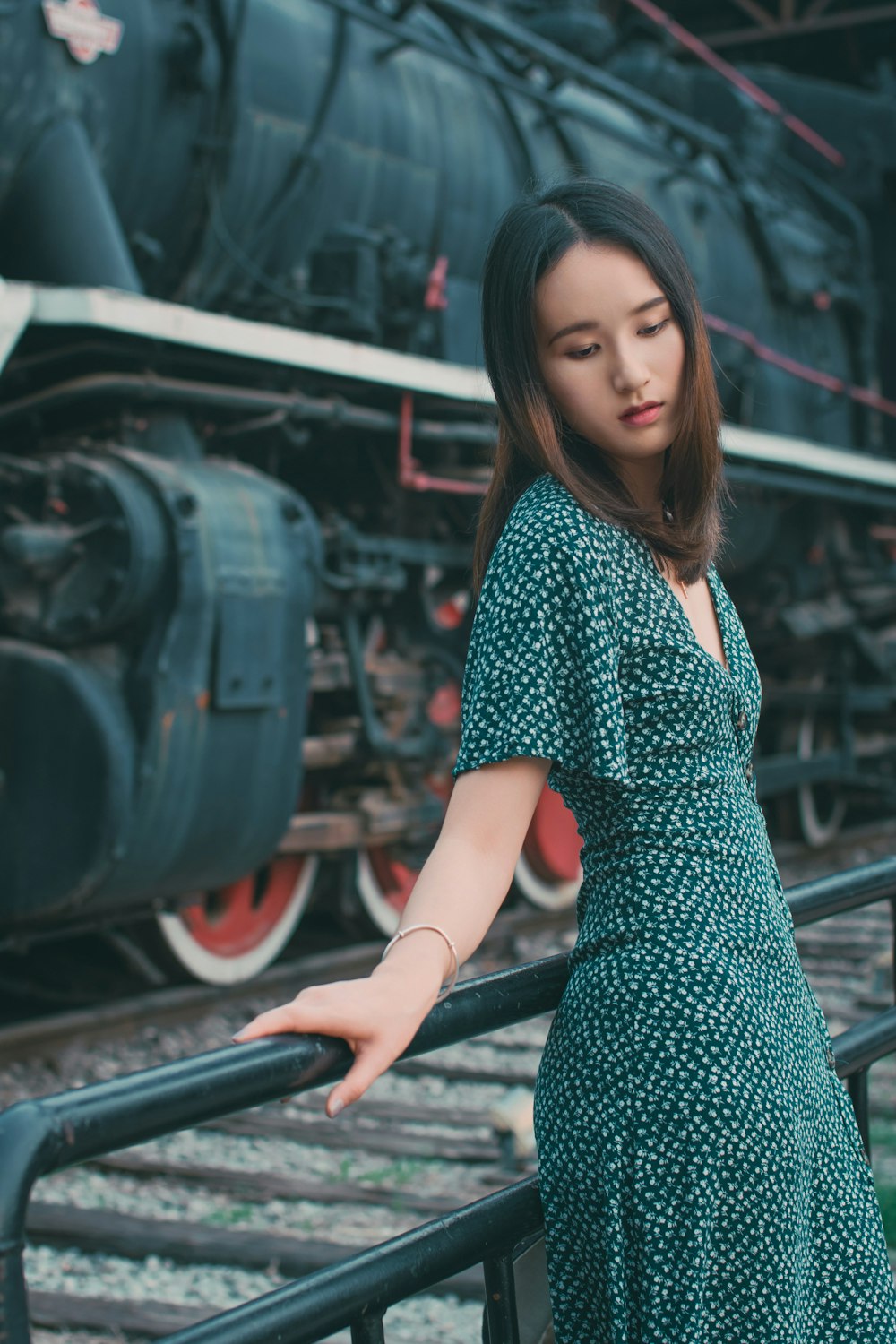 woman in blue and white polka dot dress standing on train rail