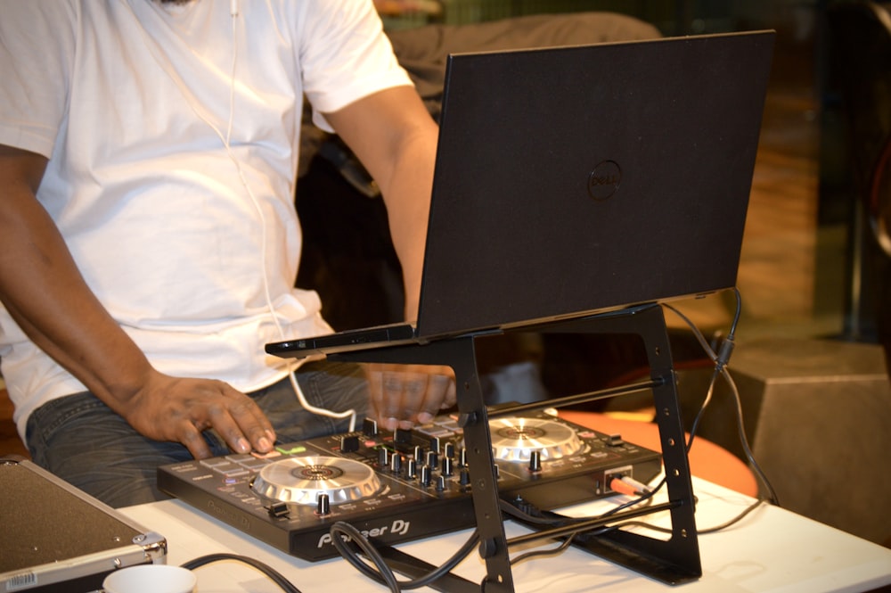 man in white shirt and black pants standing in front of black dell laptop computer