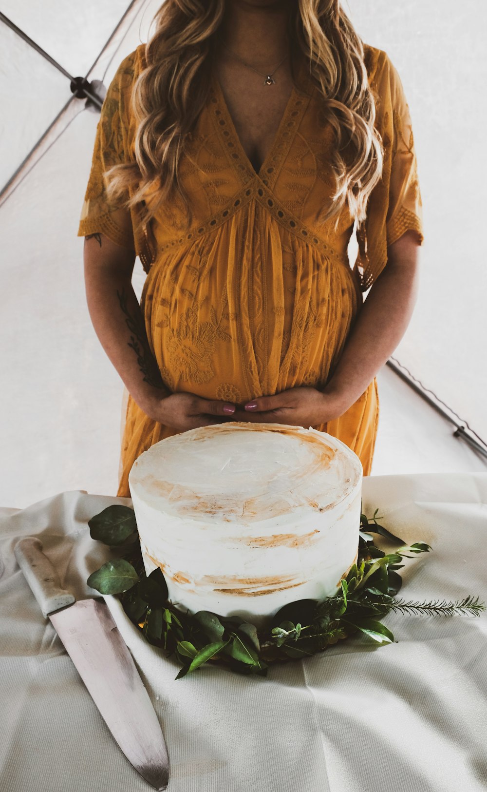 Mujer con vestido floral amarillo y blanco de pie junto a la planta verde