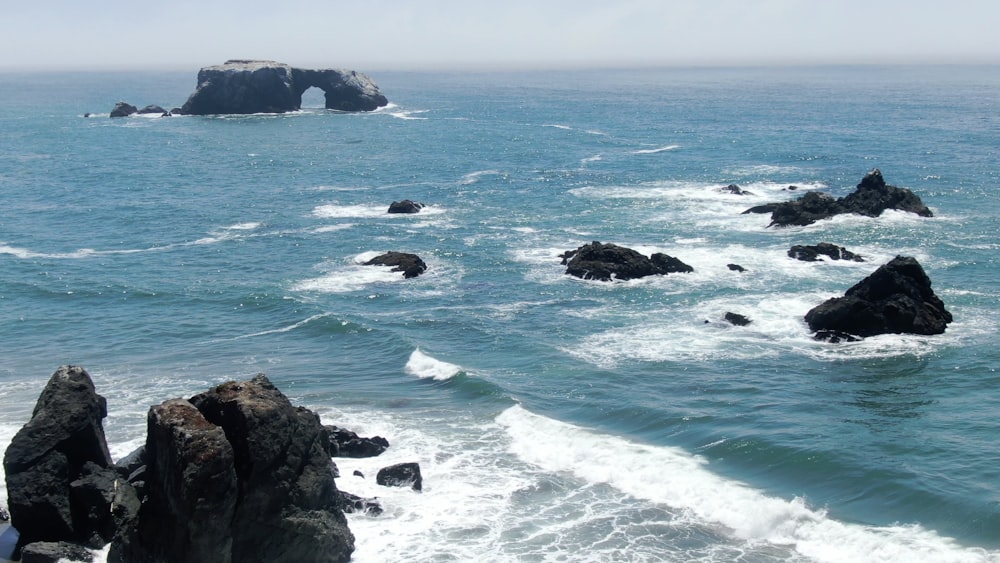 formação rochosa negra no mar durante o dia