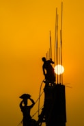 Construction site showing heavy machinery and workers installing steel structures at sunset.