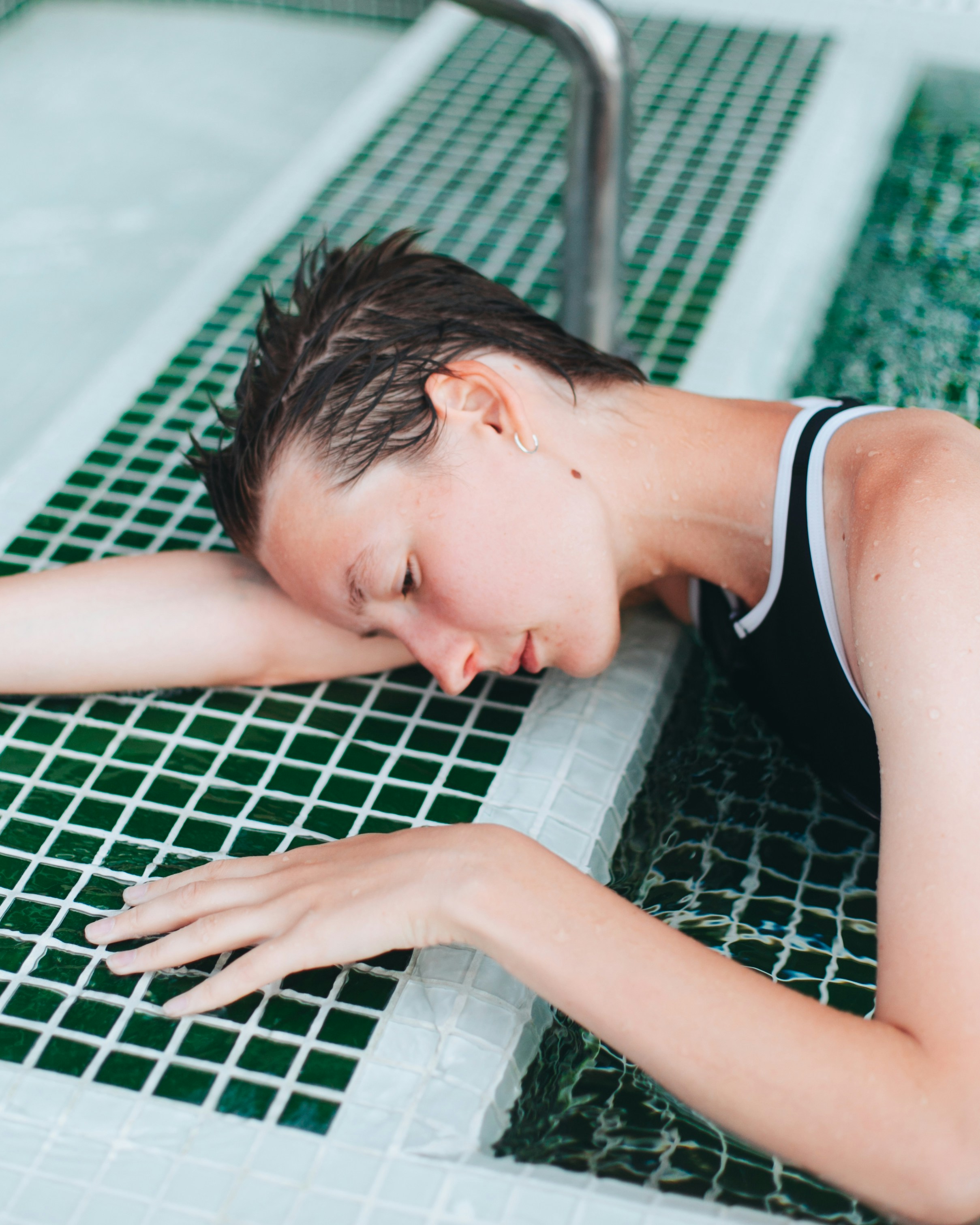 How to Stay Motivated to Work Out When You're Exhausted After Work – woman in black tank top lying on green and white ceramic tiles