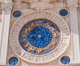 round gold and blue analog clock displaying zodiac signs