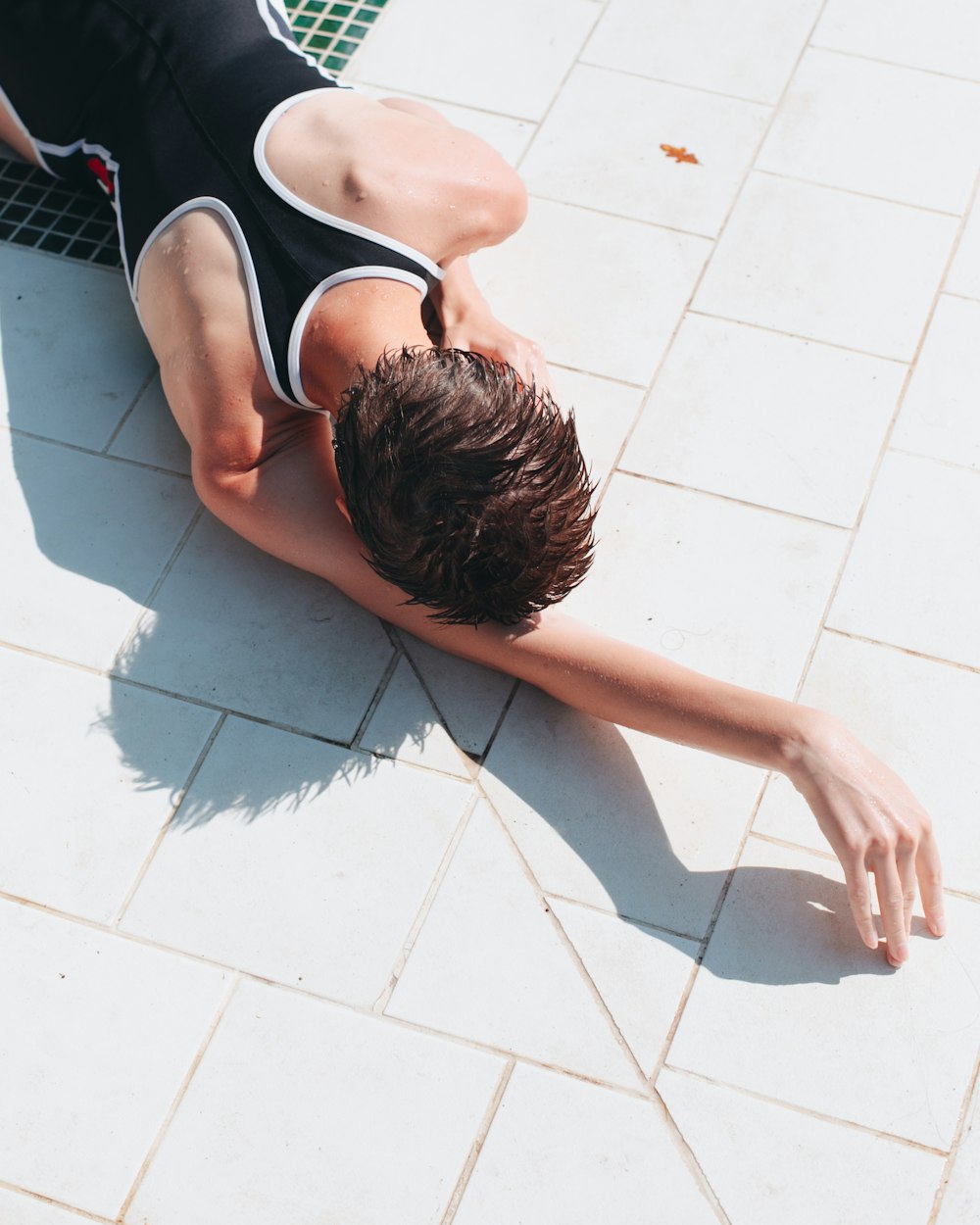 woman in black and white tank top lying on white floor tiles