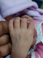 Close-up of a baby hand gently holding an adult finger.