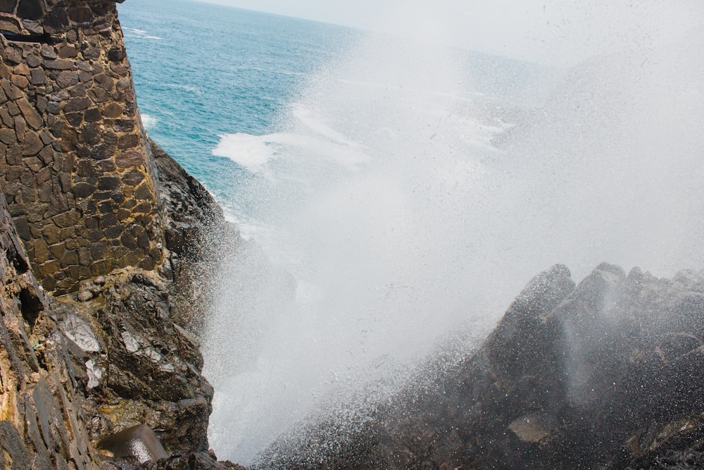 ocean waves hitting brown rocky shore during daytime