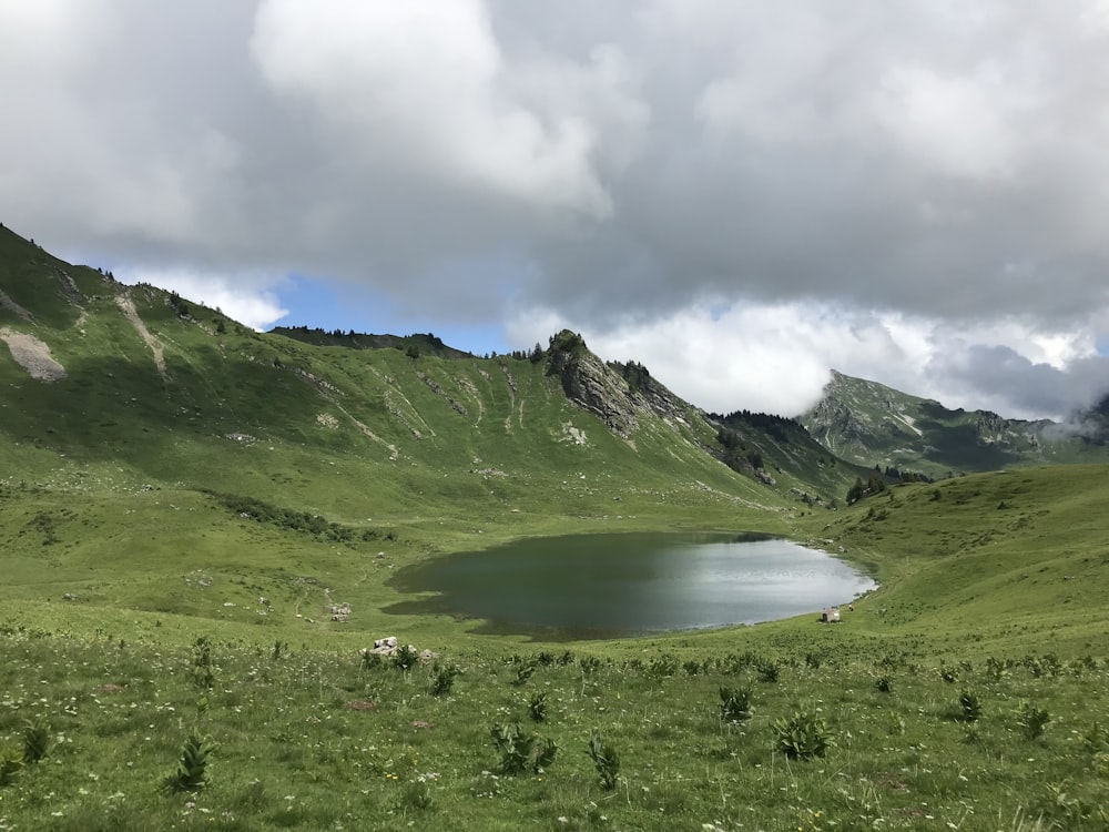 green mountains near lake under cloudy sky during daytime