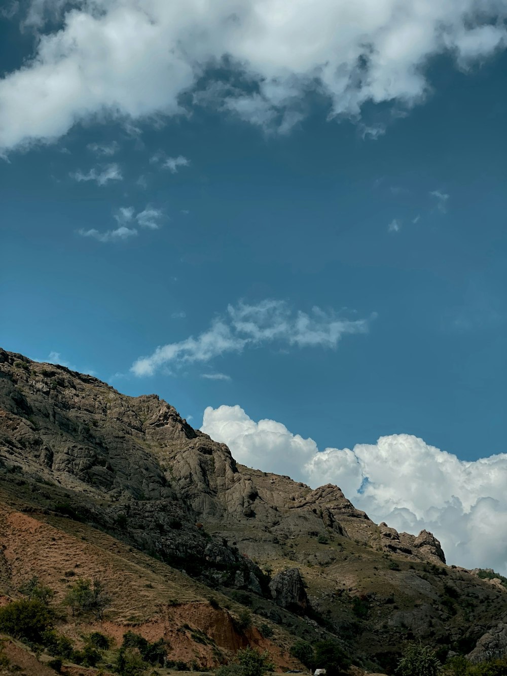 brown rocky mountain under blue sky and white clouds during daytime