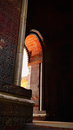 An ornate stone archway framing a sunlit courtyard filled with vibrant marigold decorations.
