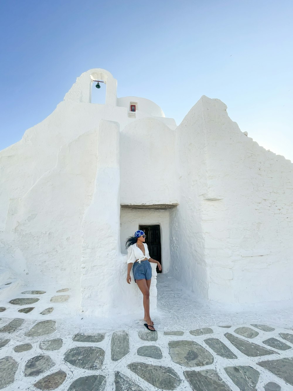 woman in blue denim shorts standing on white concrete wall during daytime