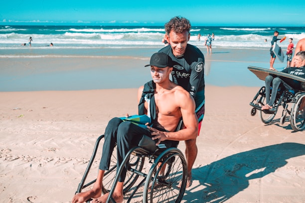 man in black shorts sitting on black wheelchair on beach during daytime