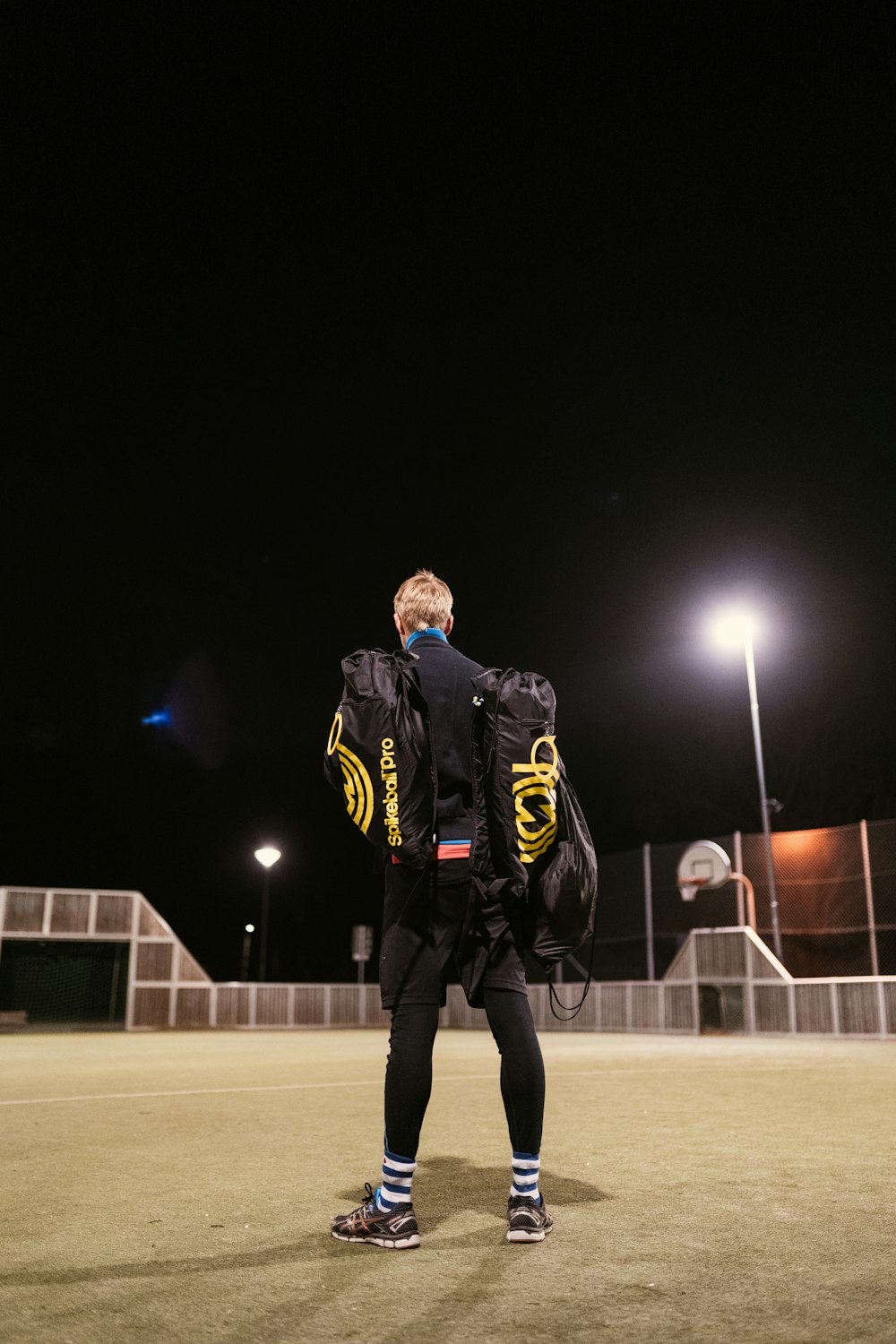 man in black and yellow jacket standing on gray concrete floor during nighttime