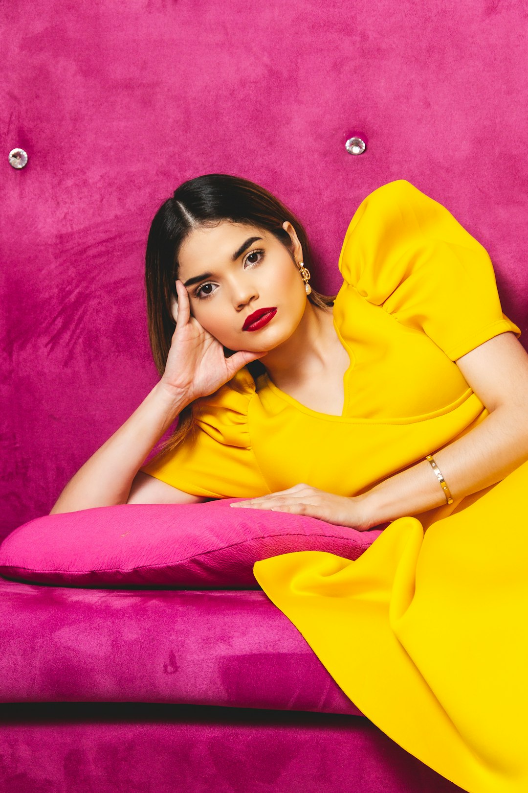 woman in yellow polo shirt lying on pink textile