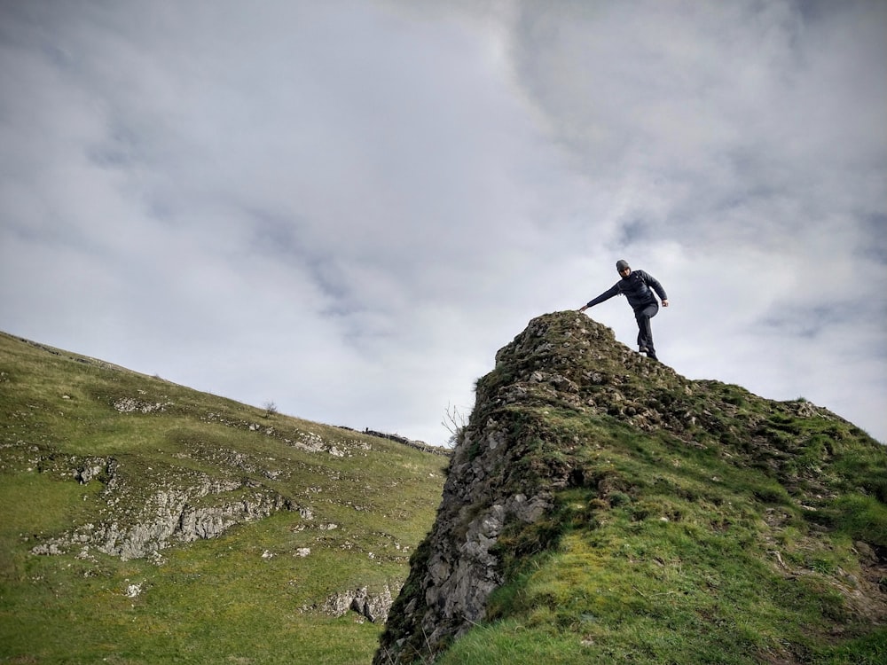 man in black jacket standing on green grass field under white cloudy sky during daytime