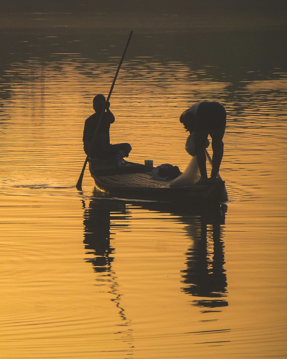 silhouette de 2 personnes chevauchant sur un bateau au coucher du soleil