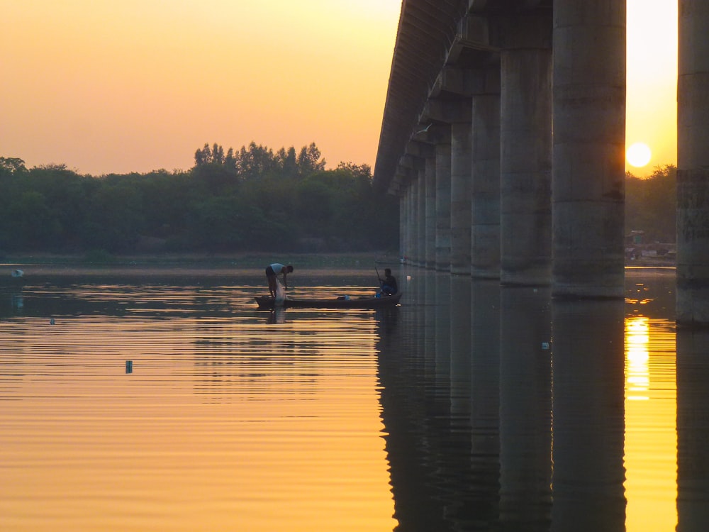 person in black shirt riding on boat on water under bridge during daytime