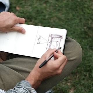 person in brown pants holding black pen writing on white paper