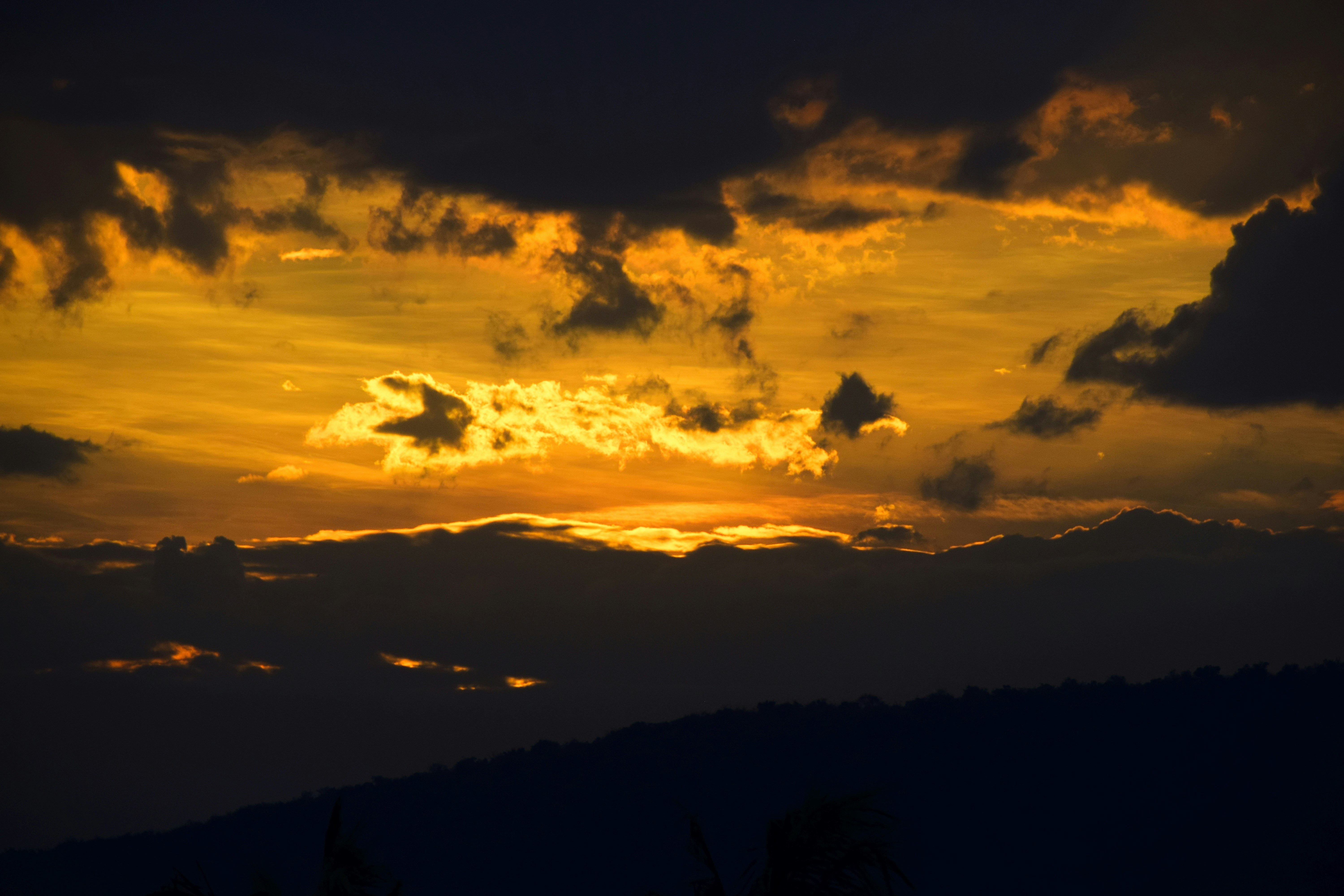 silhouette of mountains during sunset, Rain clouds at sunset.  Golden sunset with bands of dark rain clouds.