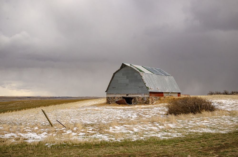 grange en bois marron sur champ brun sous ciel nuageux gris