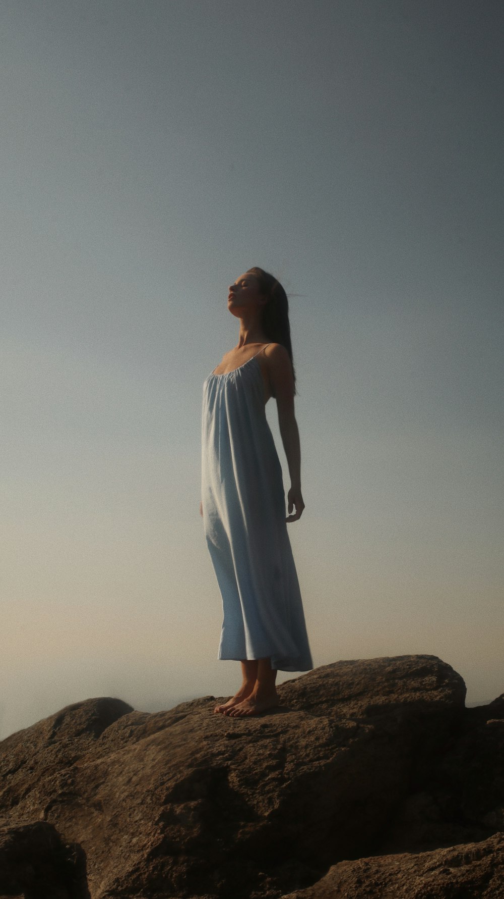 woman in white dress standing on brown rock during daytime