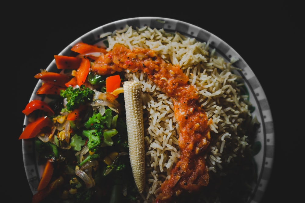 cooked rice with carrots and green vegetable on white ceramic plate