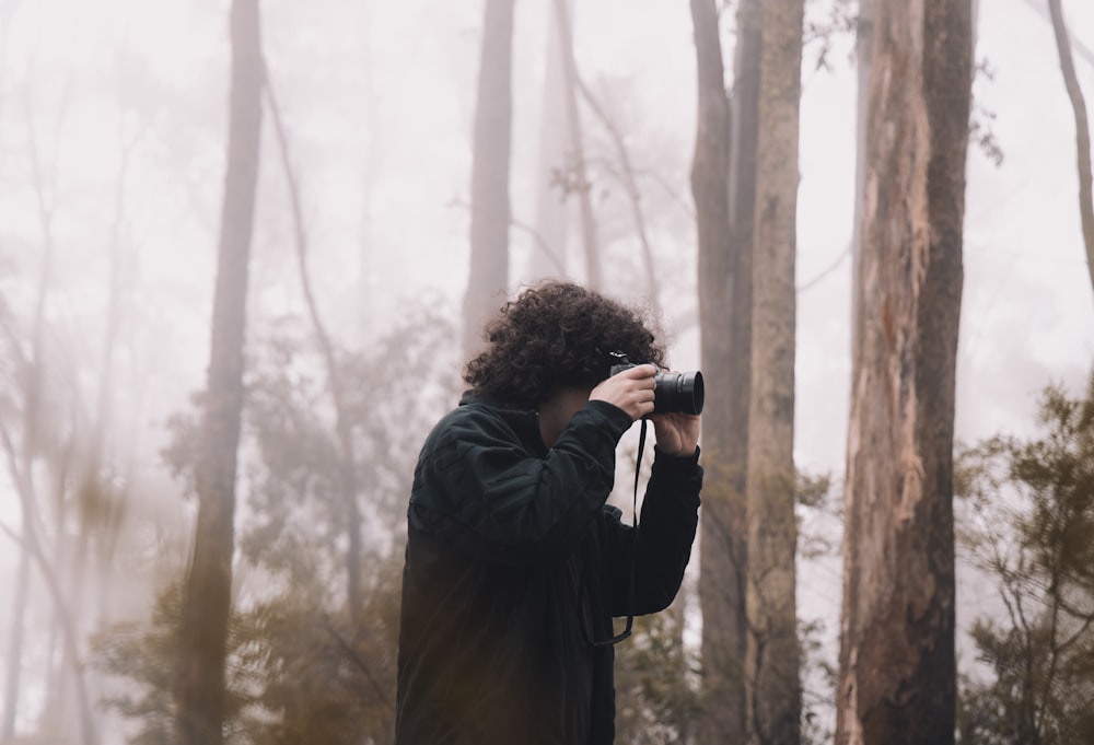 woman in black coat holding black dslr camera