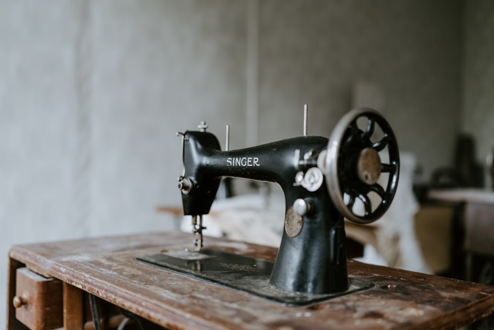 black sewing machine on brown wooden table