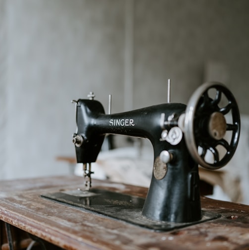 black sewing machine on brown wooden table