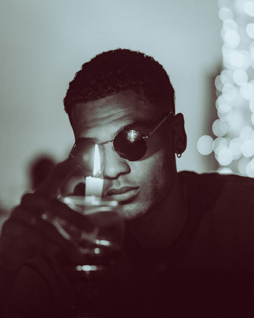 man in black sunglasses holding lighted cigarette stick