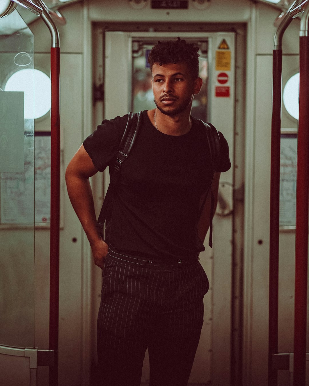 man in black crew neck t-shirt and black and white striped skirt standing near glass