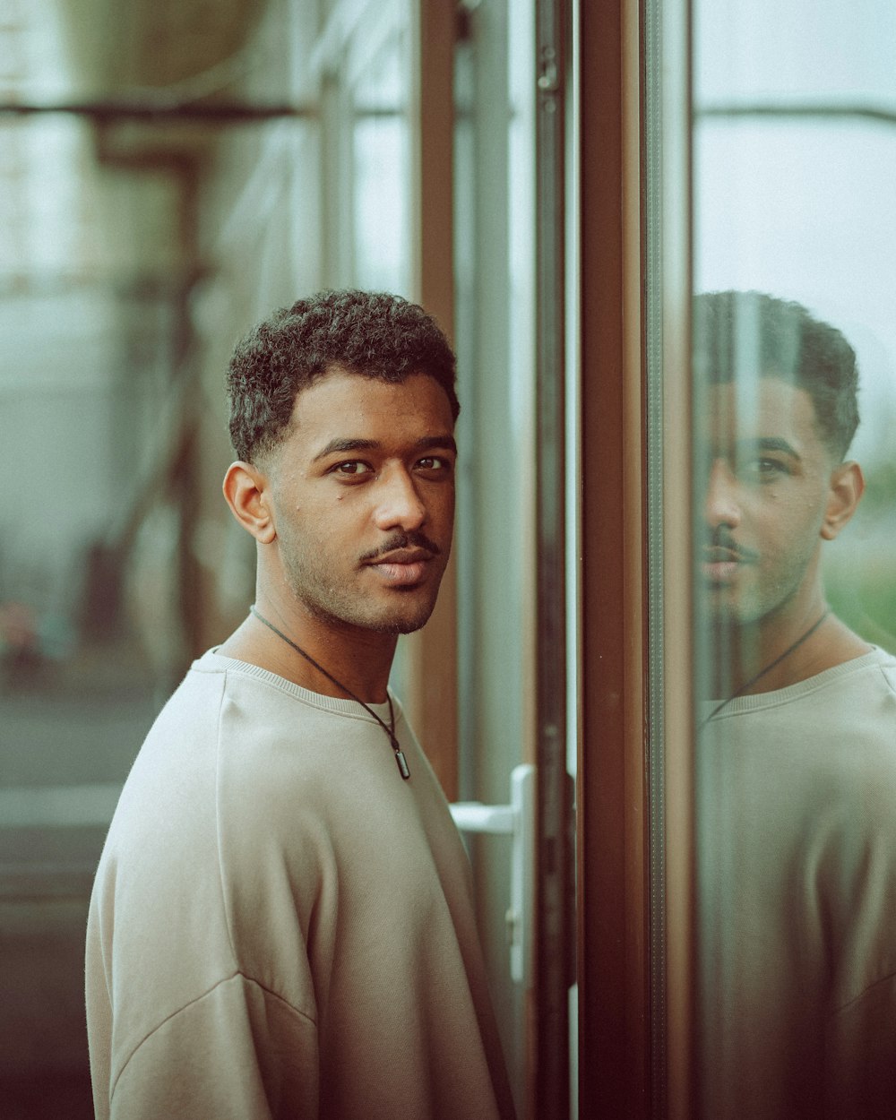 man in white collared shirt standing beside glass window