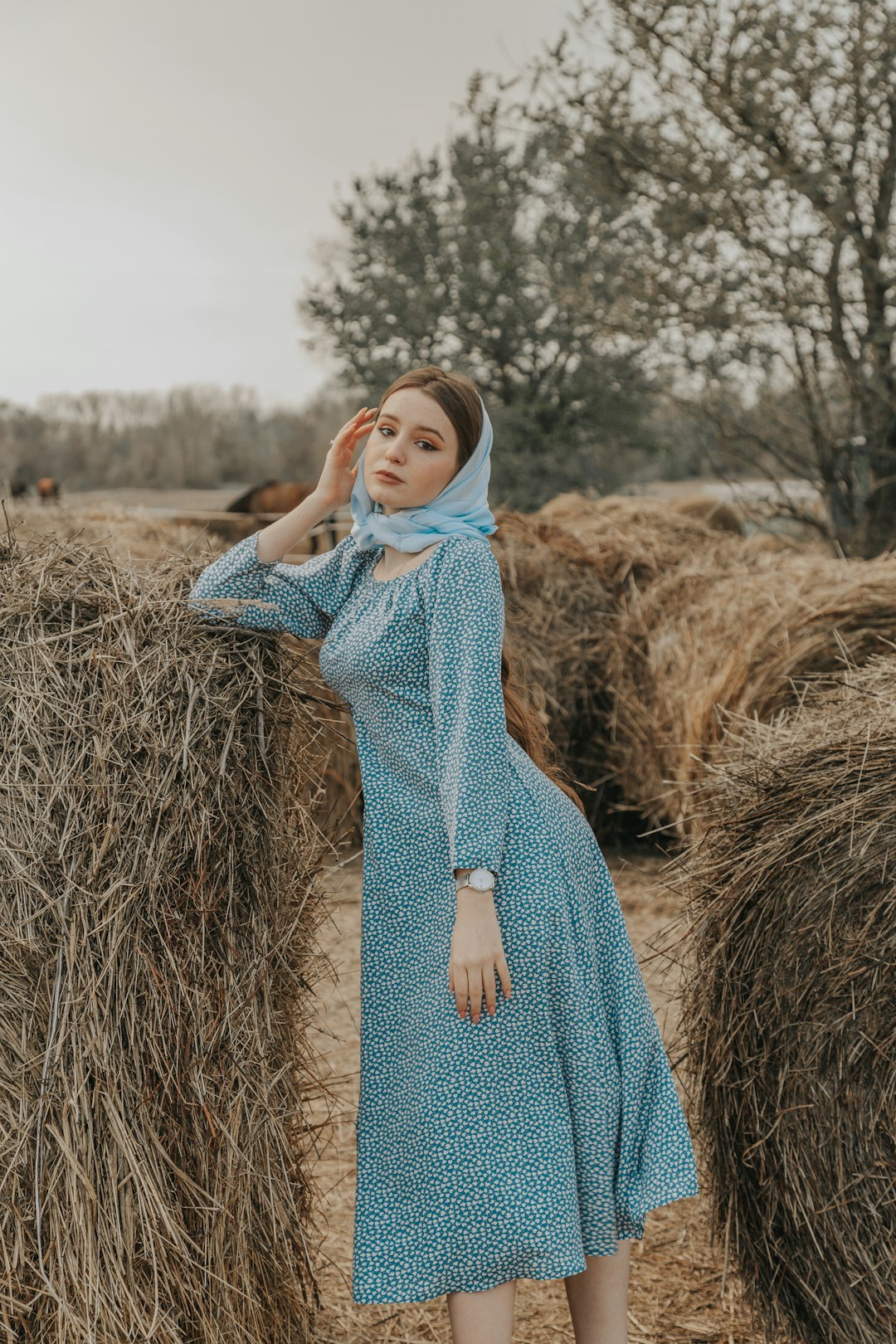 woman in blue and white floral dress standing on brown dried grass field during daytime