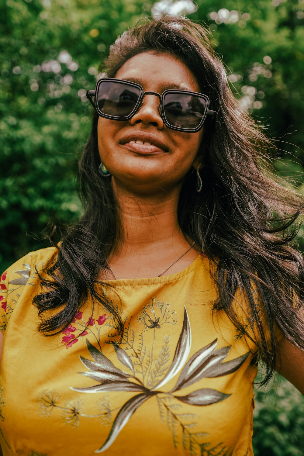 woman in yellow and white floral shirt wearing black sunglasses