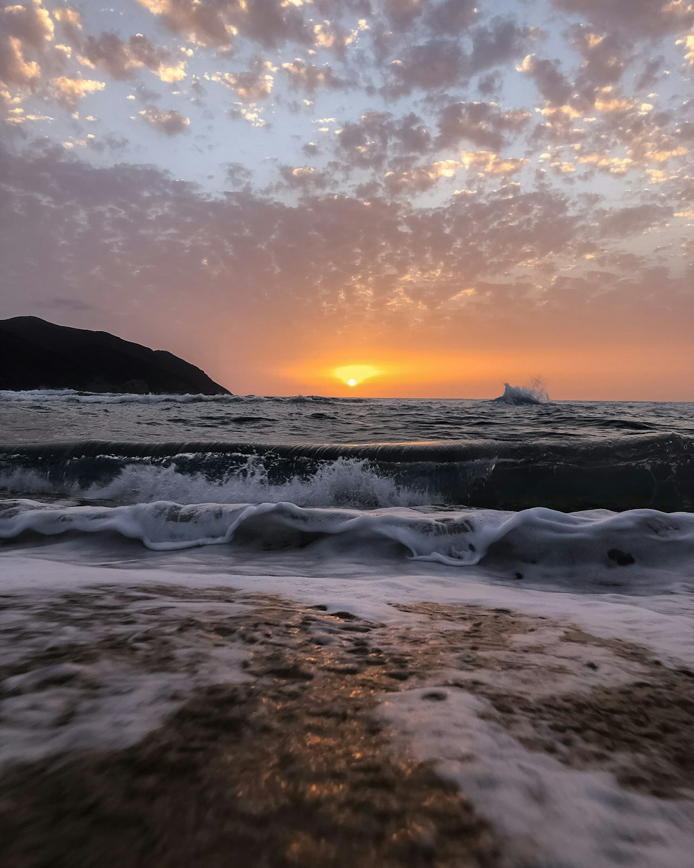 sea waves crashing on shore during sunset