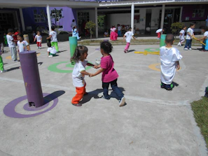The school playground bustling with children playing sports during a sunny afternoon.