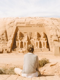 man in gray hoodie standing in front of brown rock formation during daytime