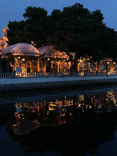 Romantic outdoor dining setup with soft lighting beside the river at dusk