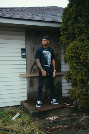 man in black crew neck t-shirt and black pants standing on brown wooden plank during